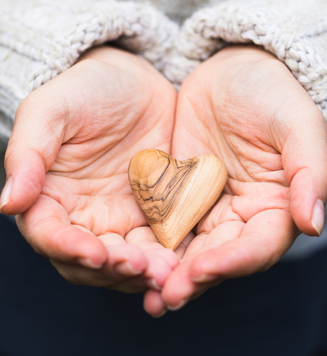 Hands holding a wooden heart