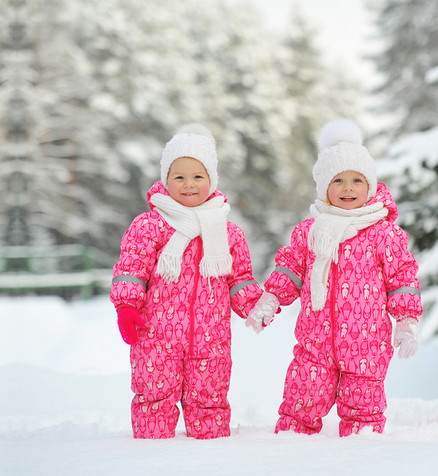 Twin toddlers holding hands in the snow